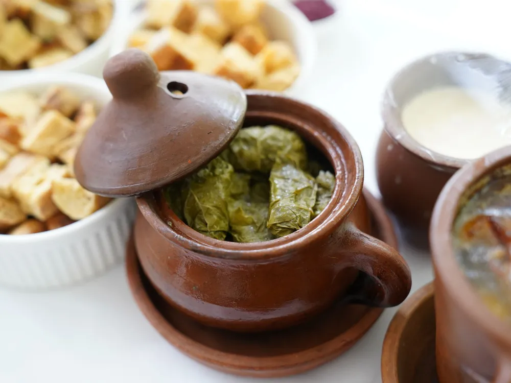 Delicious dolma served in a rustic clay pot with bread and yogurt sides for an authentic meal.
