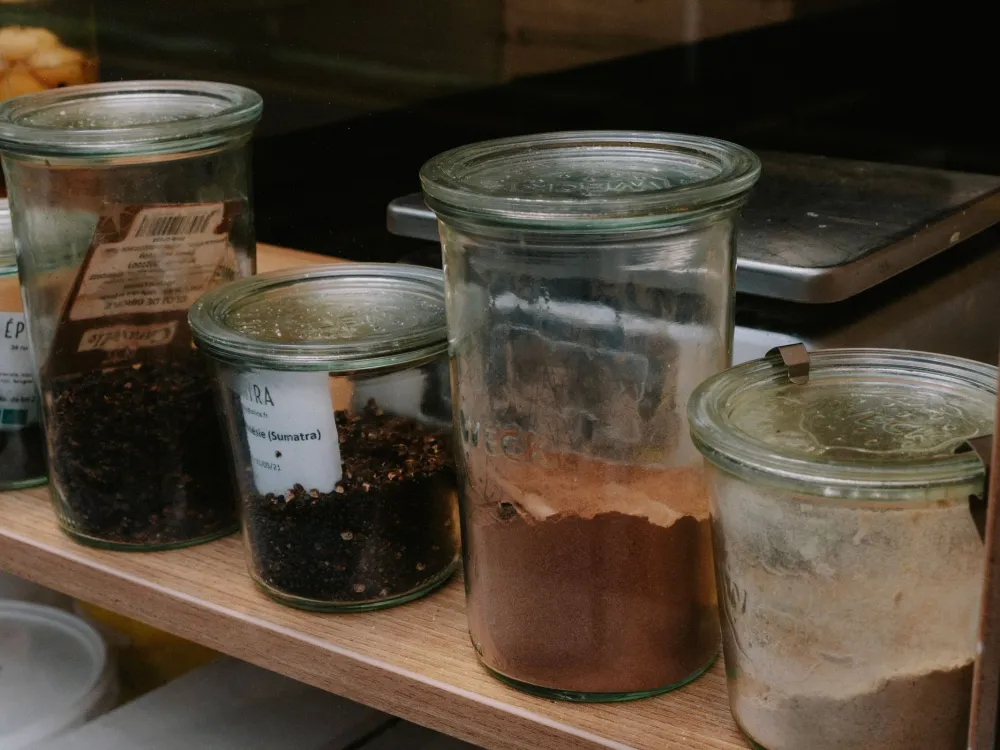 A variety of spices stored in glass jars lined on a shelf, perfect for kitchen organization.