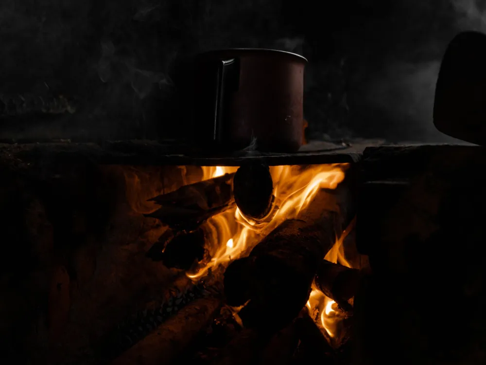 A pot heats on a traditional wood fire stove, capturing rustic cooking vibes.