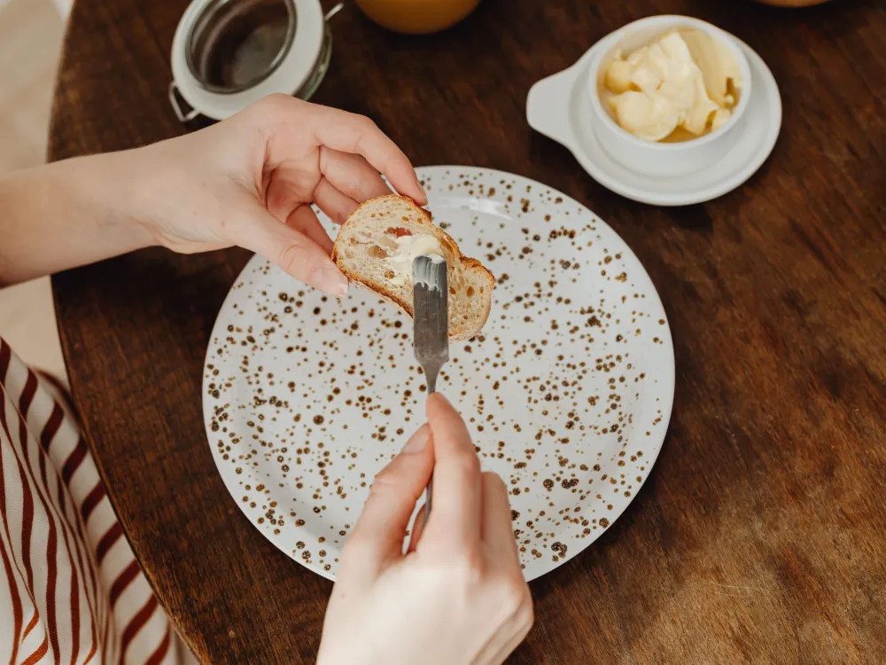 Close-up of a person spreading butter on bread for a delicious breakfast.